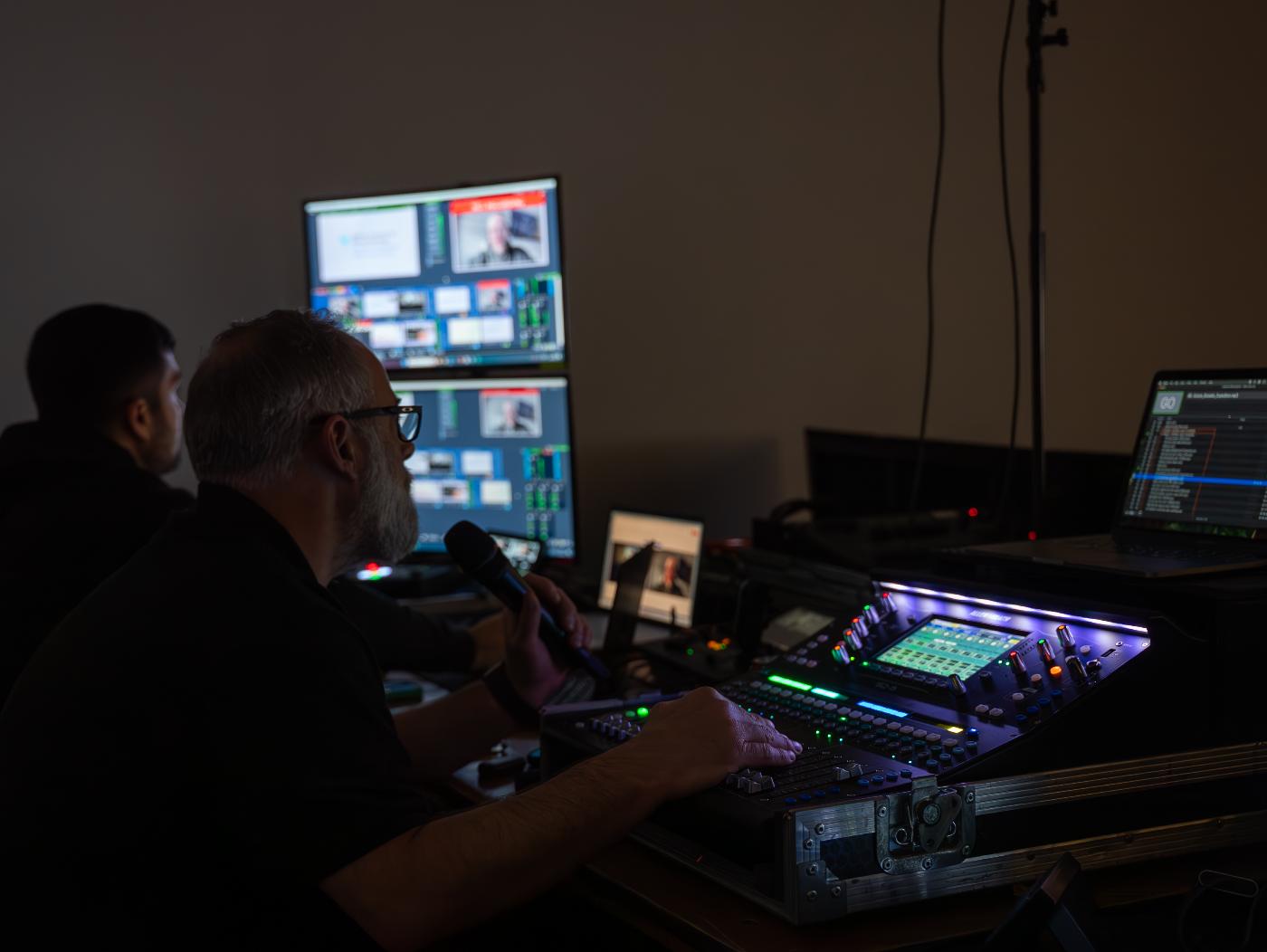 An event production technician looking over the set up for an event, including various screens and dials.
