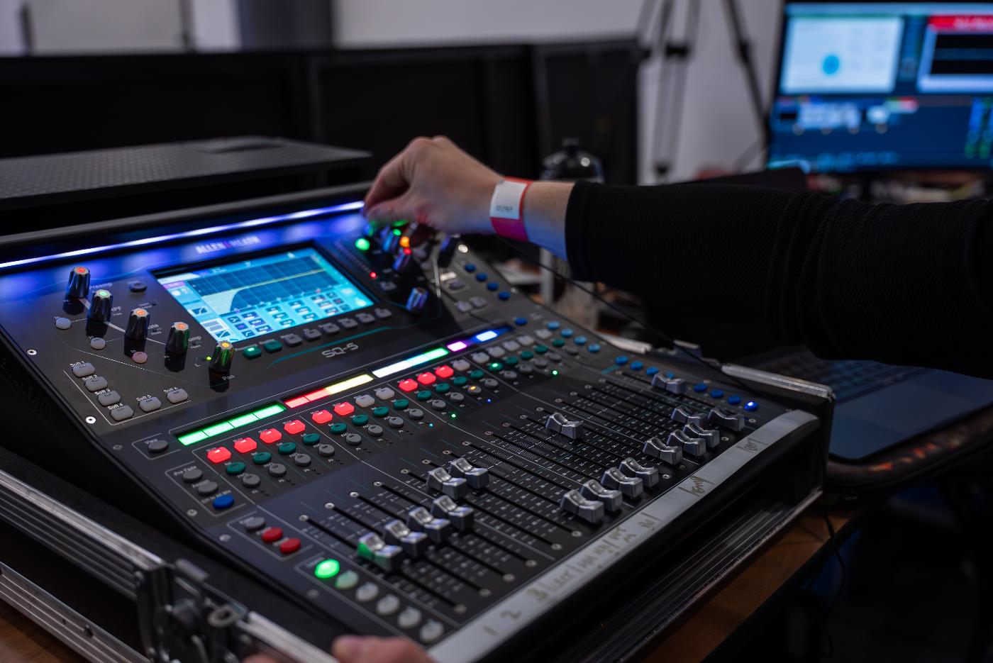 A person using a mixing desk, often used for controlling sounds and lights in event production.
