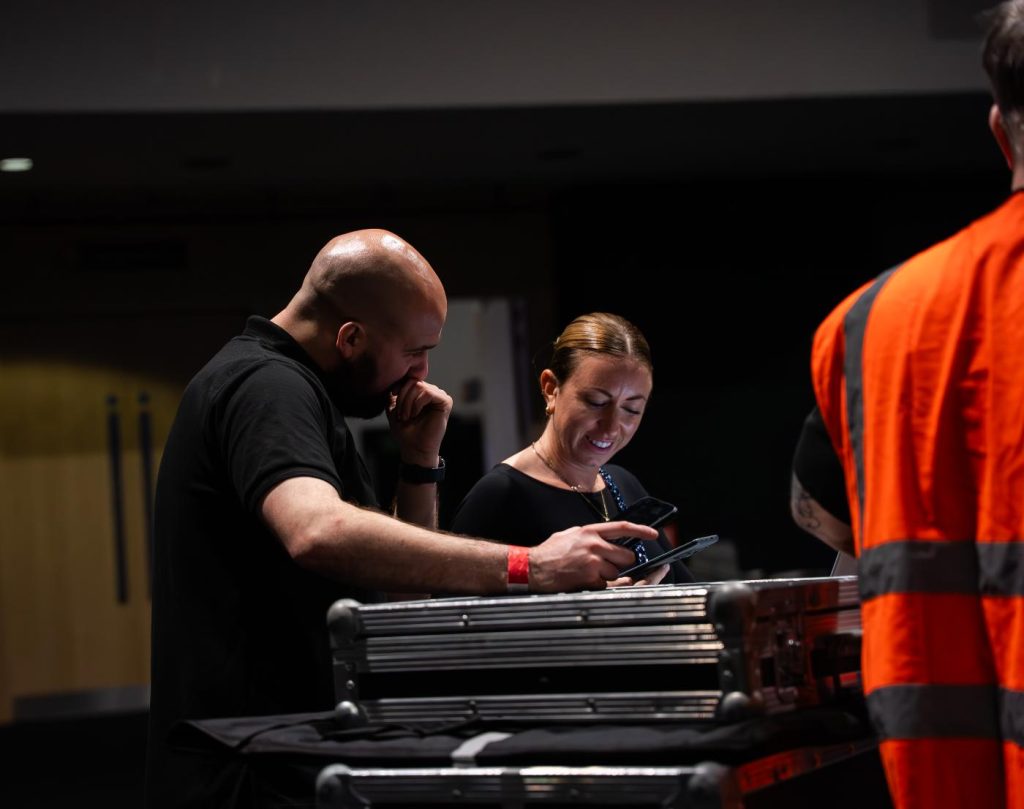 Two people looking at event production equipment together. They are smiling as they talk.