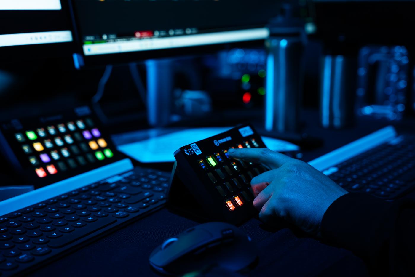 A hand pressing a button on a programmable deck, often used in event production.