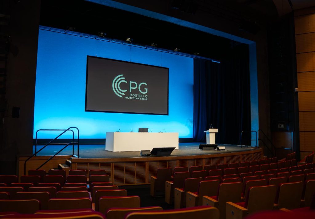 A theatre stage displaying the Costello Production Group logo.