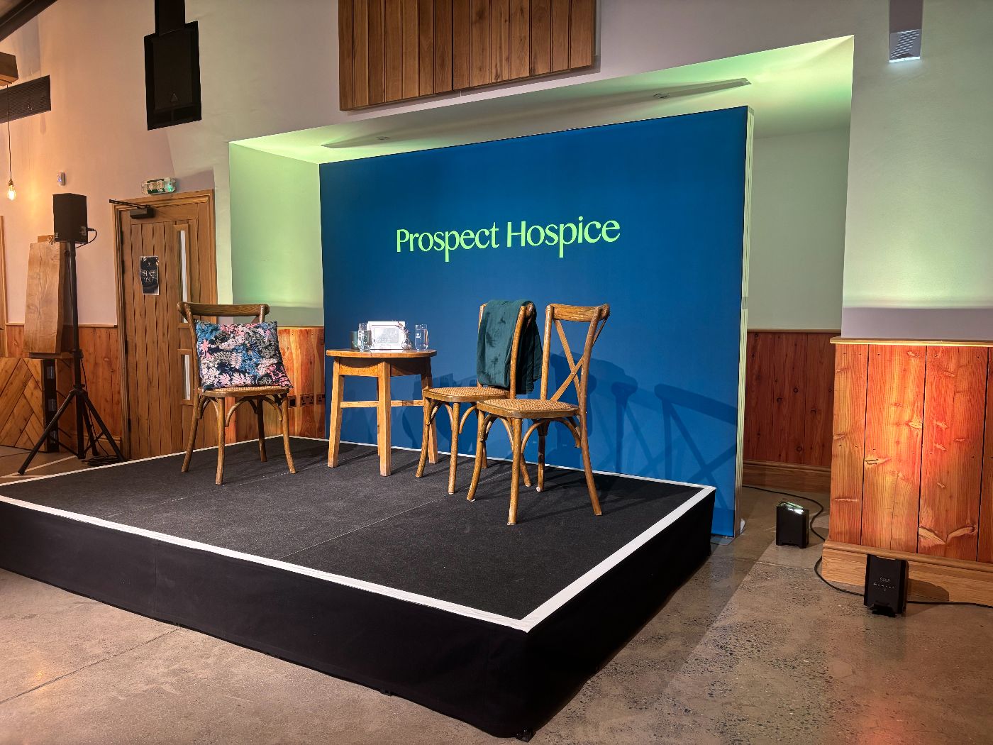 The prospect hospice event stage, with a few chairs for the presenters, and a branded backdrop.