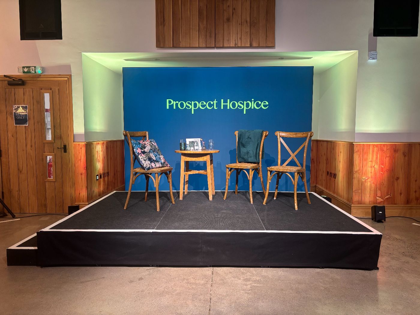 The prospect hospice event stage, with a few chairs for the presenters, and a branded backdrop.