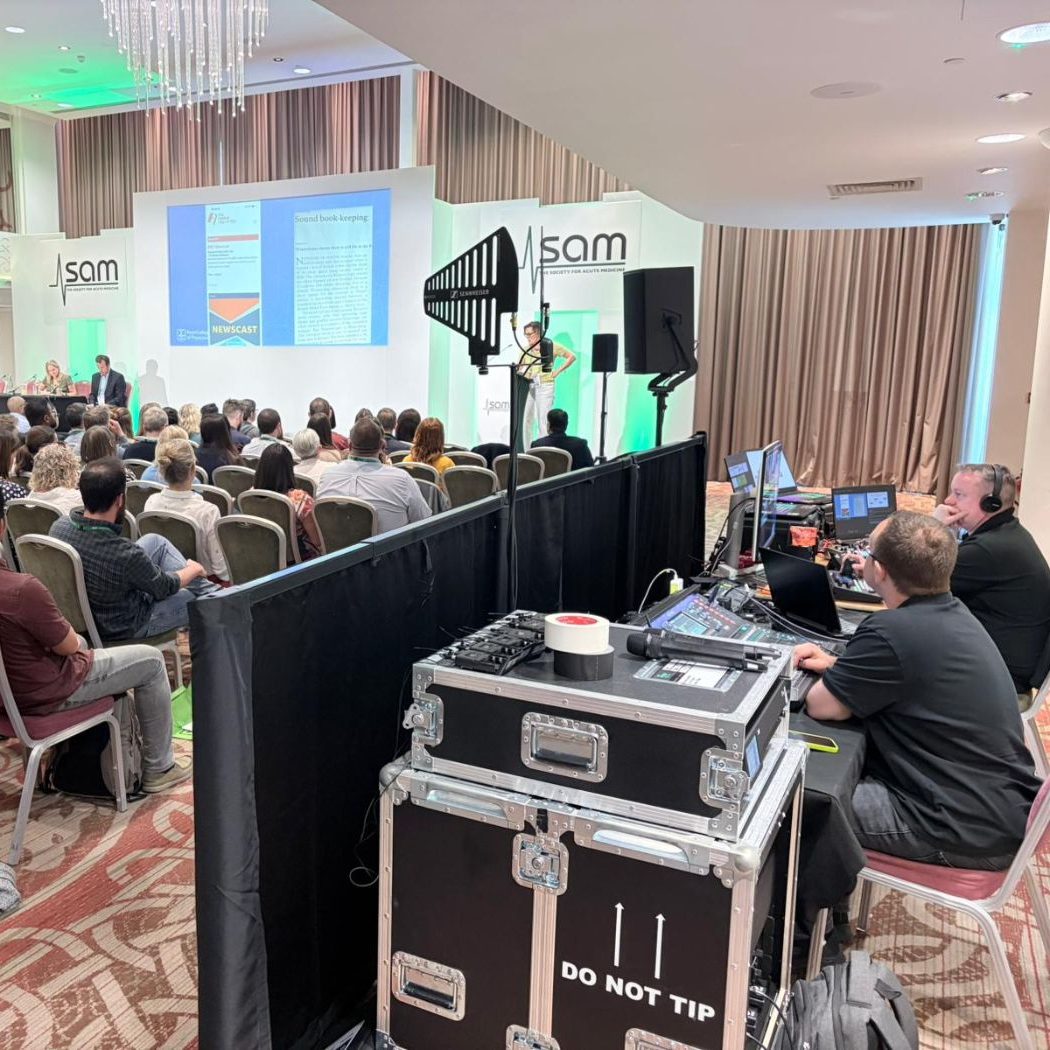 Event production technicians at work within a room with a stage and audience.